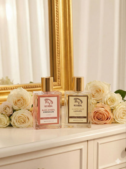 Two perfume bottles on a surface with flowers and a decorative mirror in the background Red Vocal Bad Angel For Women & White Oud Luxury Premium Perfume Set for Unisex | Long-Lasting Eau De Toilette | Women & Unisex | 2 × 100ml Combo