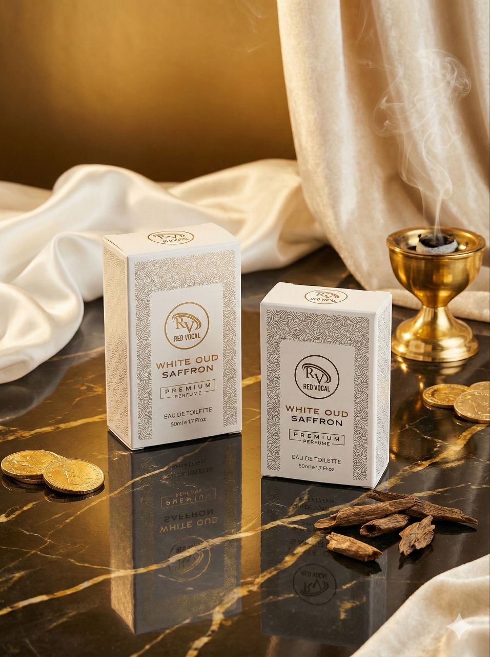 Two boxes of White Oud Saffron perfume on a reflective surface with gold coins and a candle.