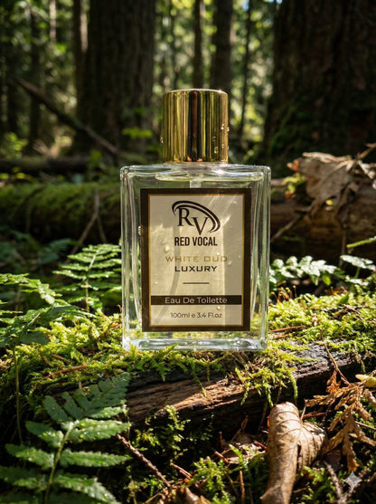 Perfume bottle labeled 'Red Vocal' on a log in a forest setting Red Vocal White Oud Luxury Premium Perfume Eau De Toilette – Unisex 100ml Bold & Long-Lasting Fragrance